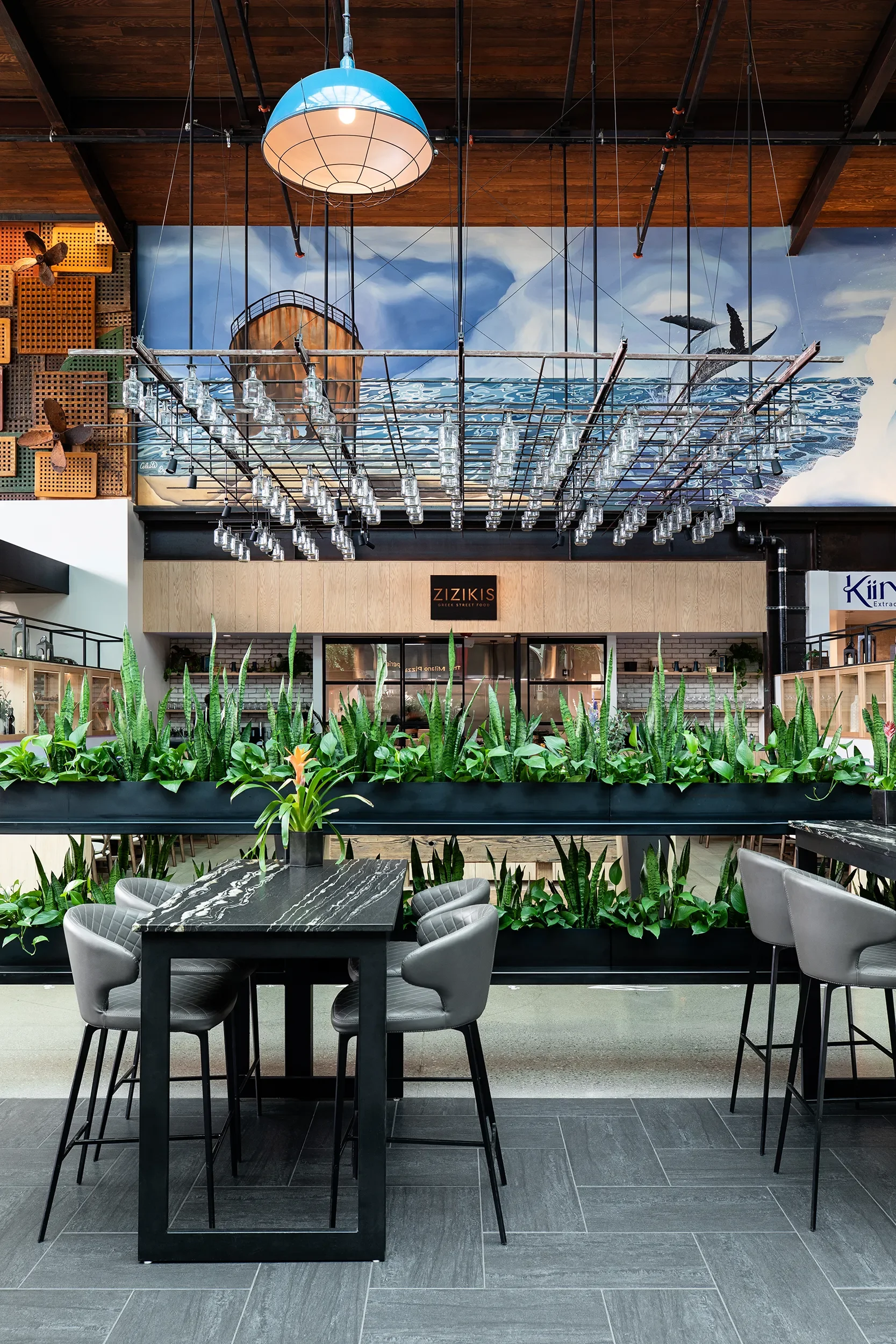 Suspended glass rack and planter rail above communal dining tables at Skydeck in Del Mar
