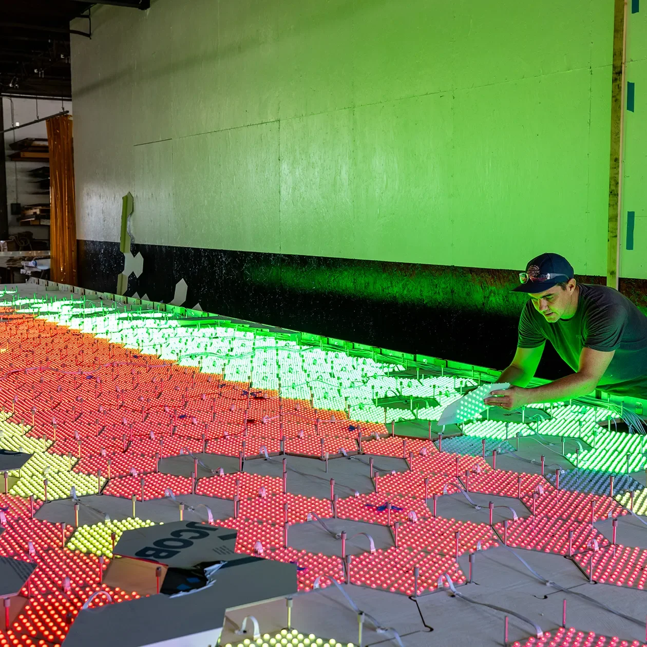 Fabricator assembling a lit panel array for a feature wall on the shop floor at Tecture in San Diego