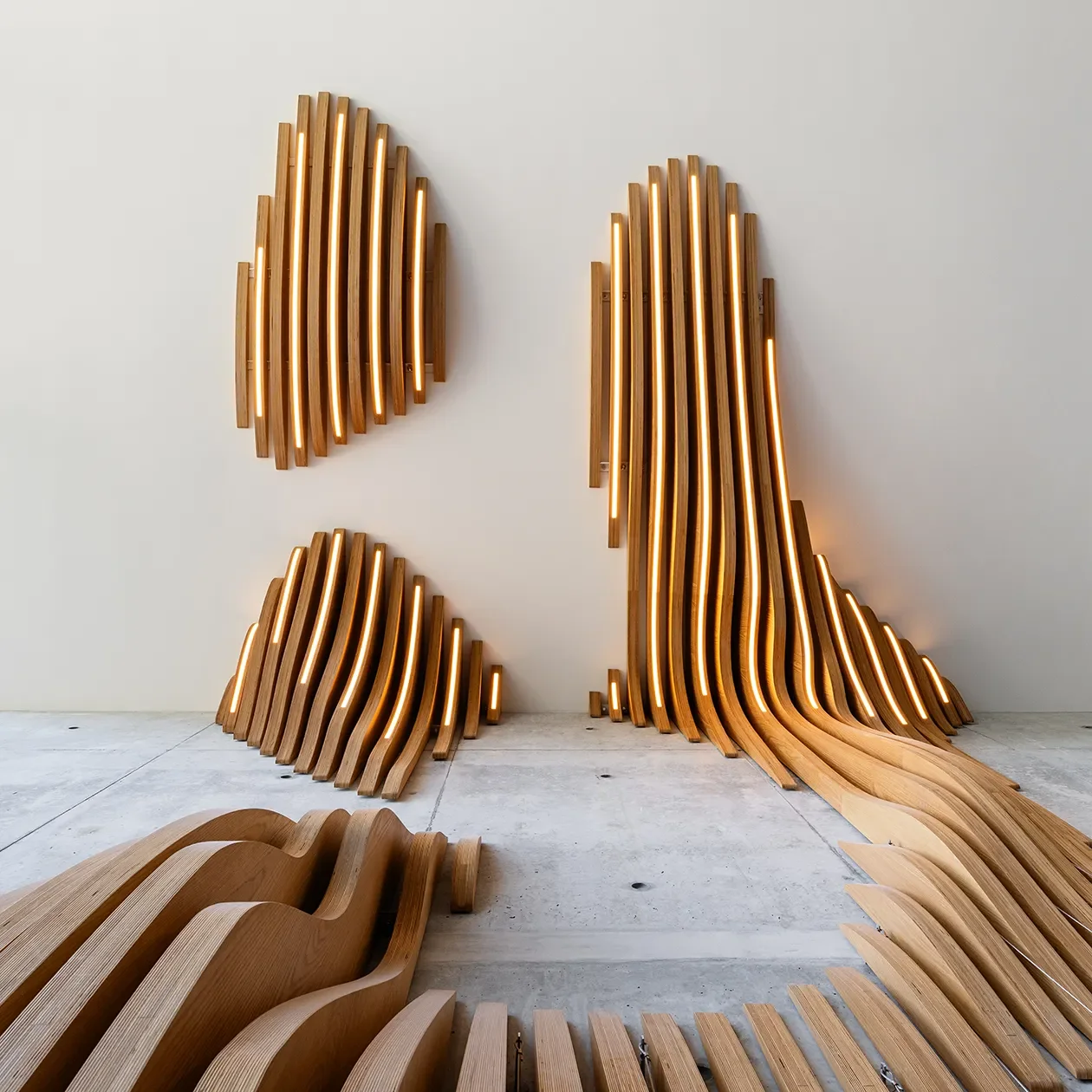 Curved wood slat sculpture sections standing in the shop before installation