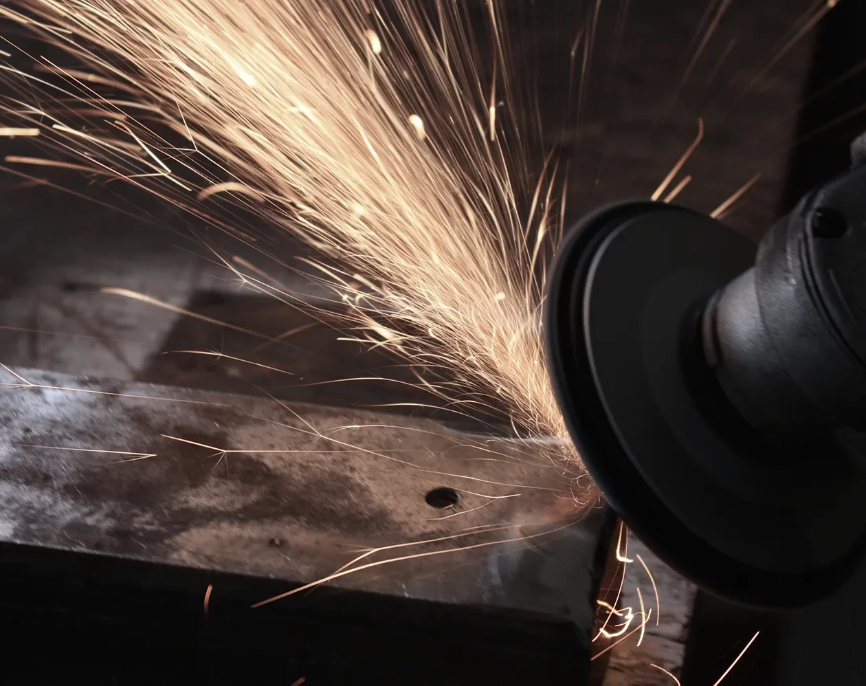 Grinding a welded steel component in the Tectuer metal shop with sparks flying.