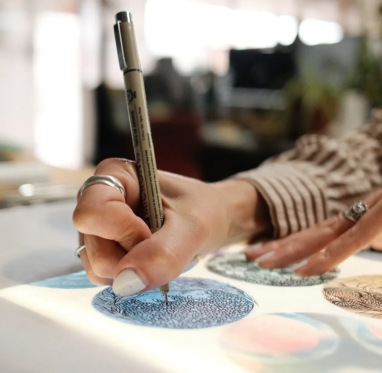 Designer sketching a detail over material samples during the design assist phase of a new project concept.