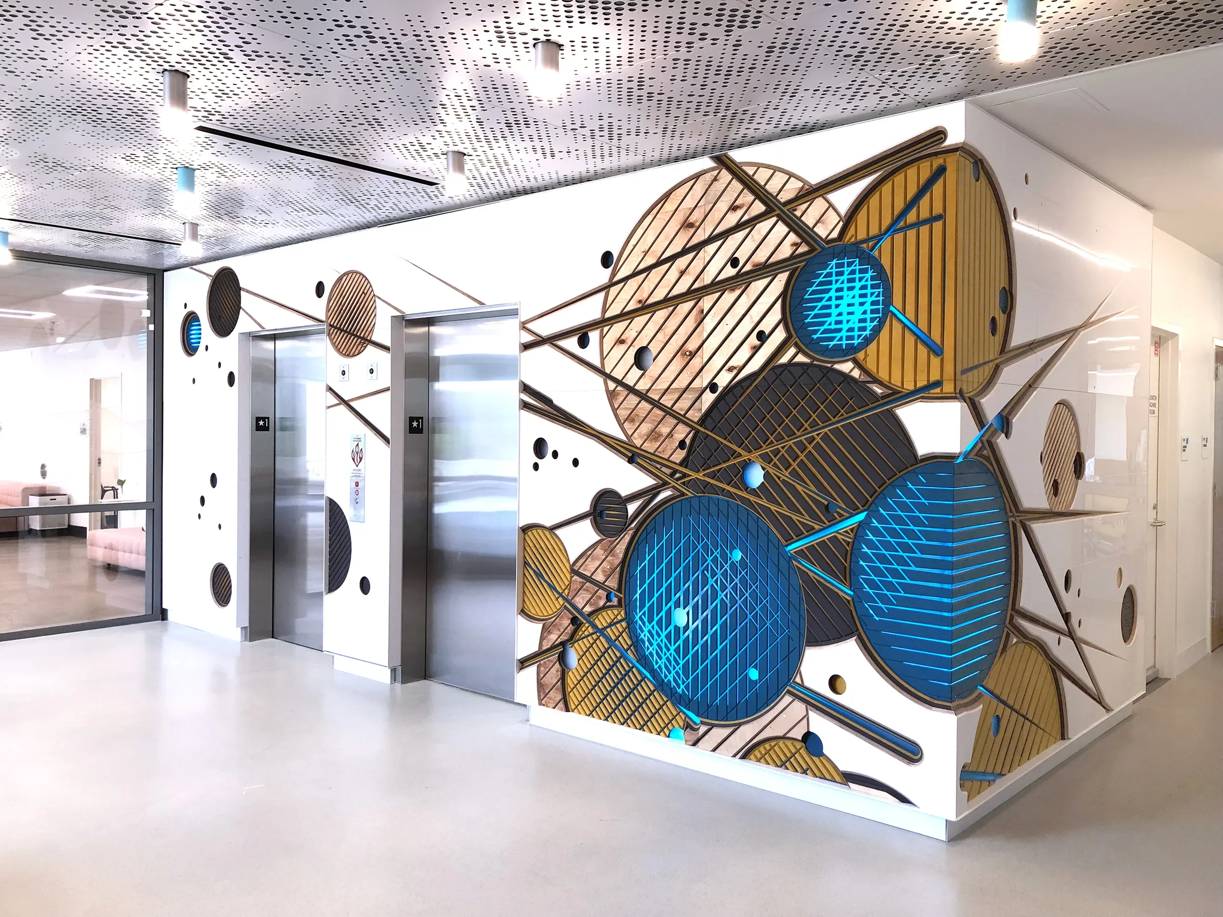 Data field, layered ble and wood tone discs wrapping an elevator core at the UC San Diego data science institute