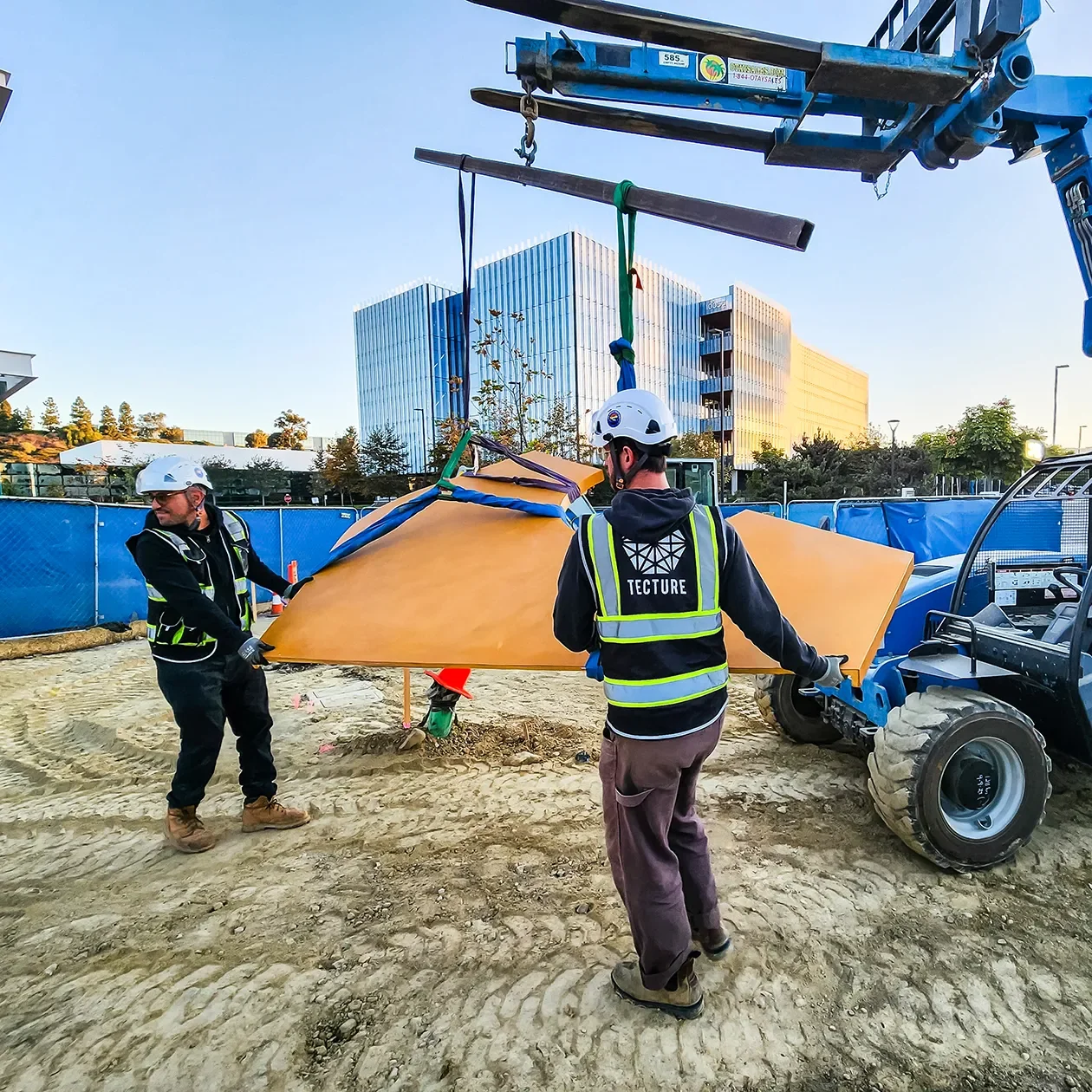 Install crew rigging a curved wood panel from a telehandler on site