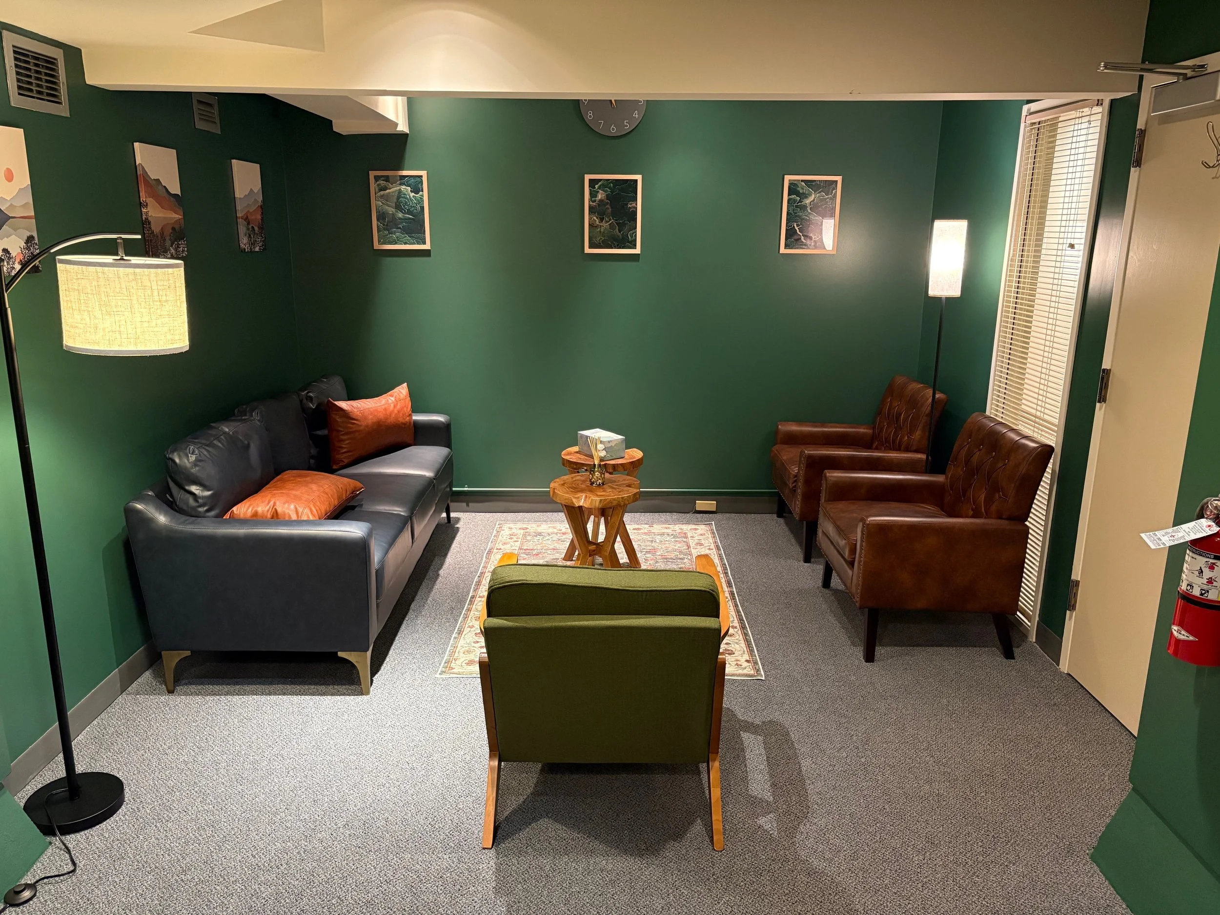 Therapy office at Humanistic Therapy NW Portland — comfortable seating area with navy sofa, green walls, and warm lighting