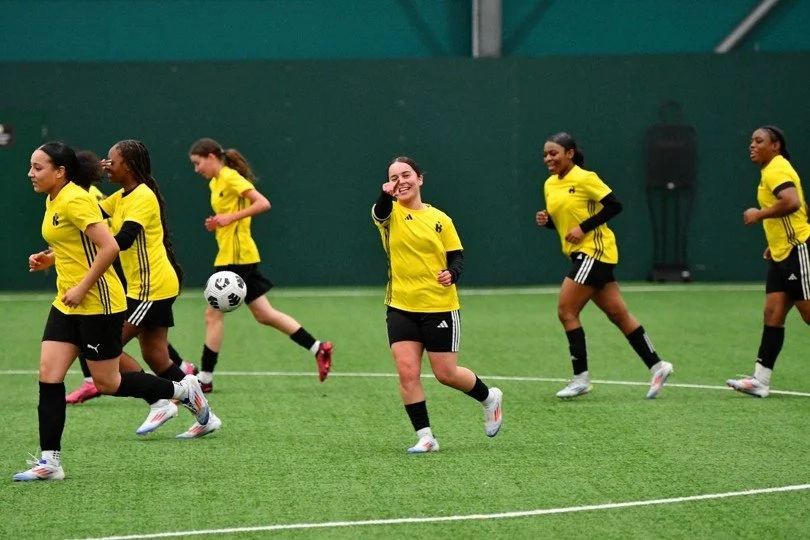 Players in yellow Kinetic training shirts jogging on an indoor pitch