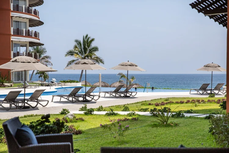 Lawn, pool, palms and the ocean seen from the ground-floor terrace of Unit 1212, Laguna building, Vivo Resorts