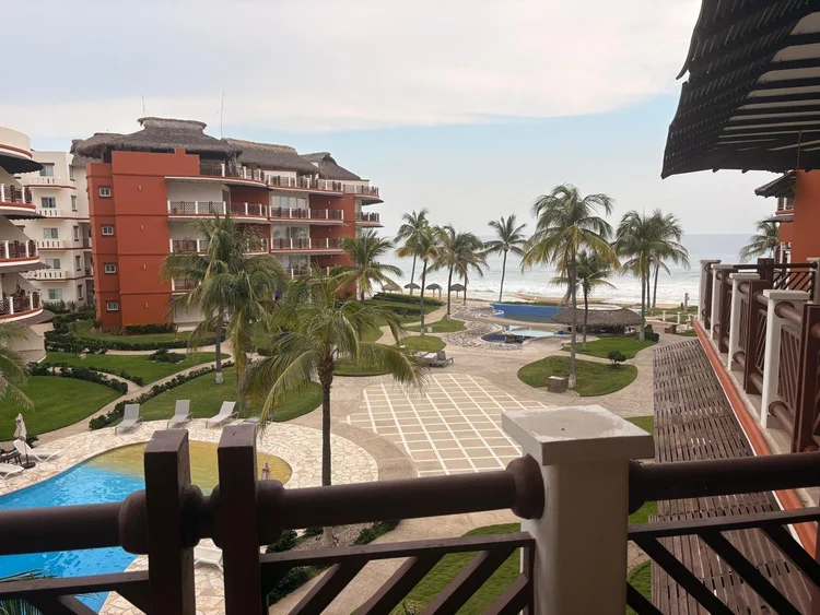Balcony view over the pools and palms to a partial ocean view from Unit 233, Building B, Vivo Resorts