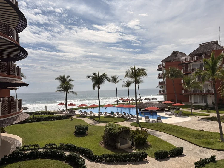 View over the palms, lawns and pools to the ocean from Unit 424, Building D, Vivo Resorts