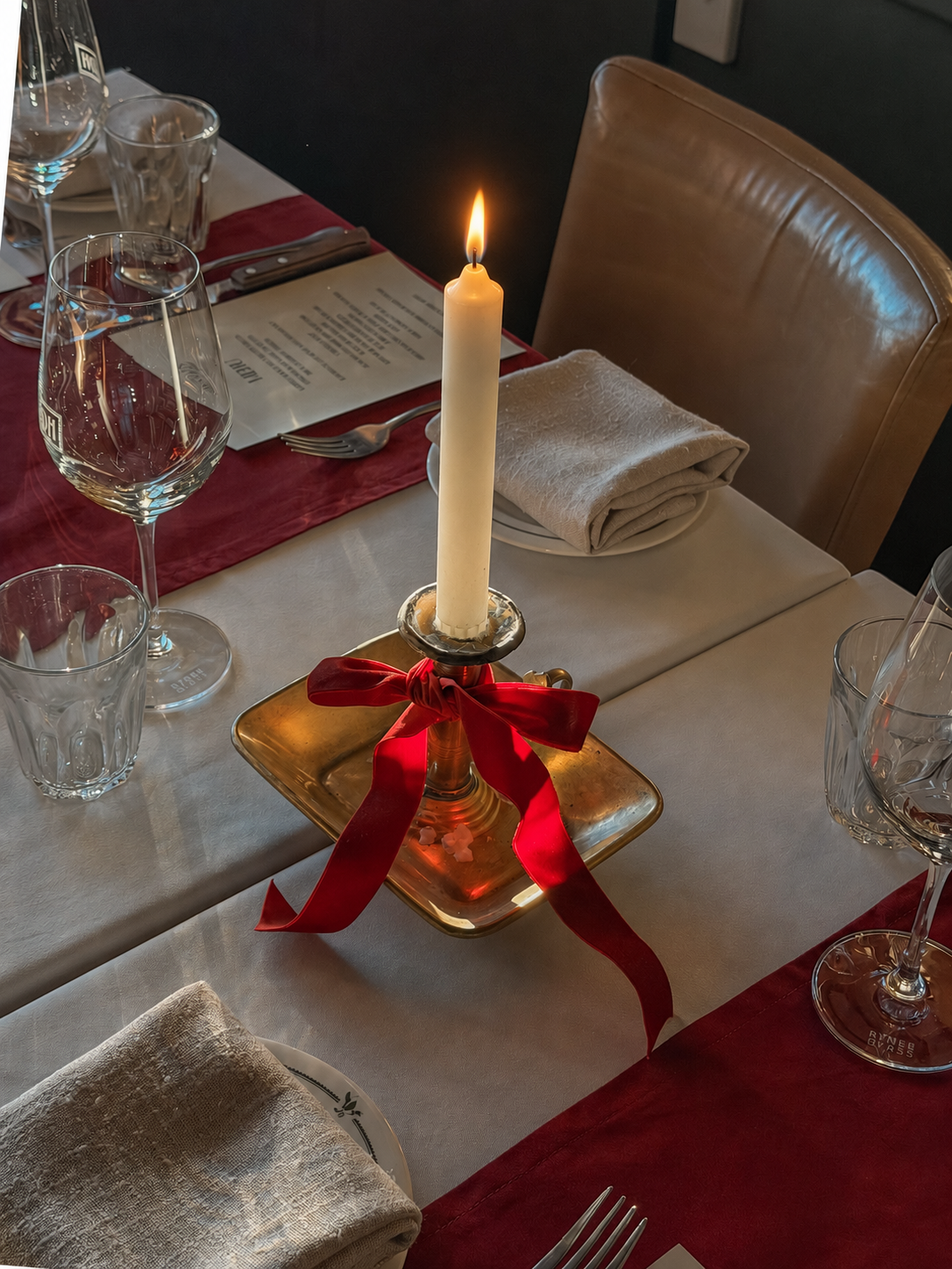 A candle tied with a red Christmas bow on the table