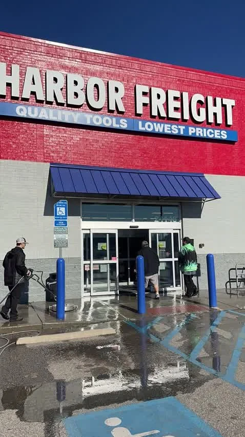 V&G crew pressure-washing a commercial storefront and sidewalk