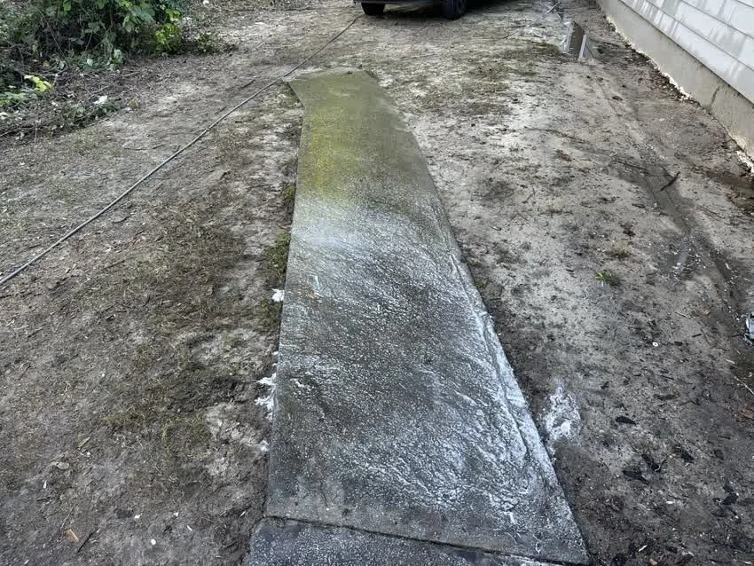 Dramatic clean line on a pressure-washed driveway, dirty concrete on one side, restored concrete on the other
