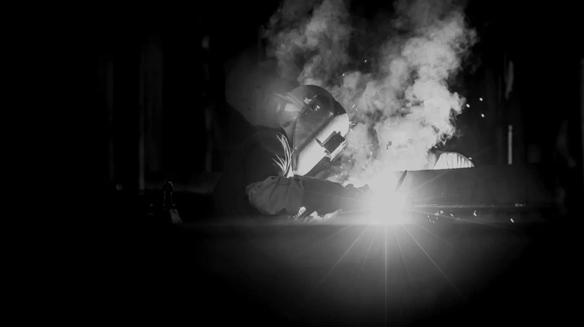 Welder working at Dallaire Contracting with smoke and bright welding arc