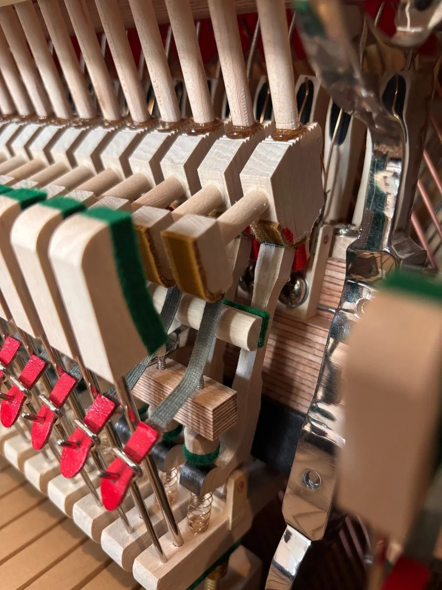 Close-up of the wooden components and felt inside an upright piano action.