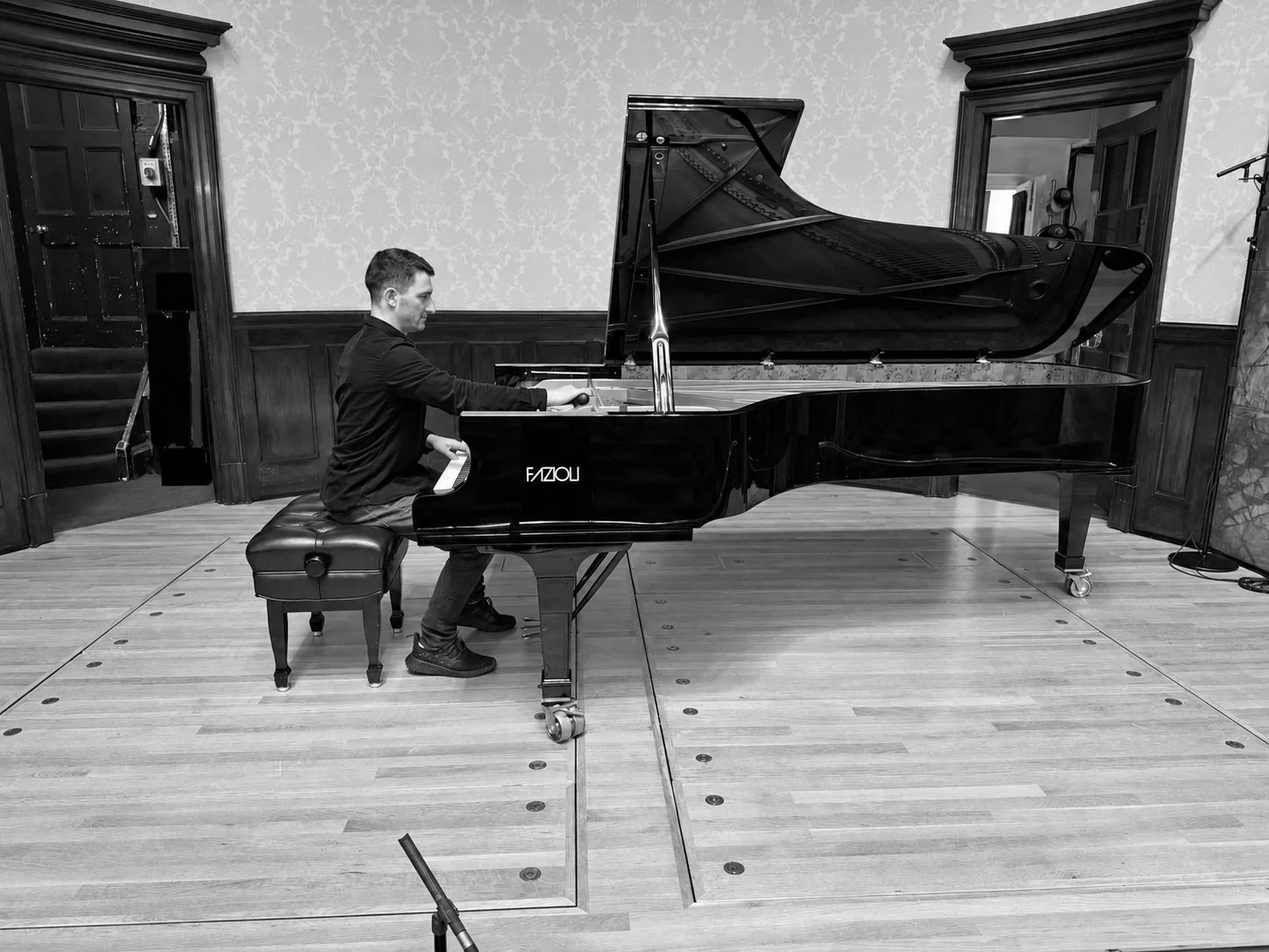 Adam Ogrodzinski tuning a Fazioli grand piano in a concert hall
