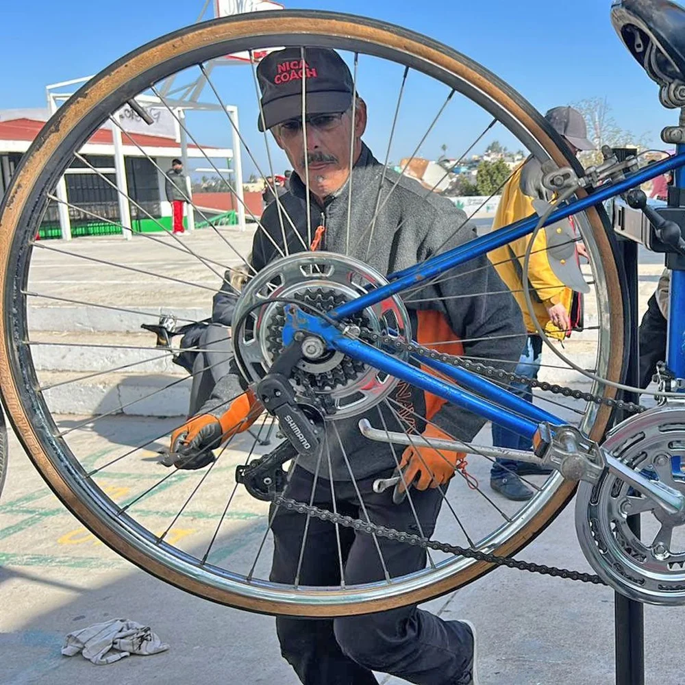 A volunteer mechanic framed by a bicycle wheel