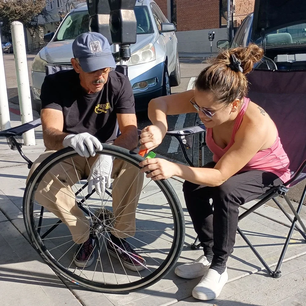 A volunteer mechanic shows a rider how to seat a tire