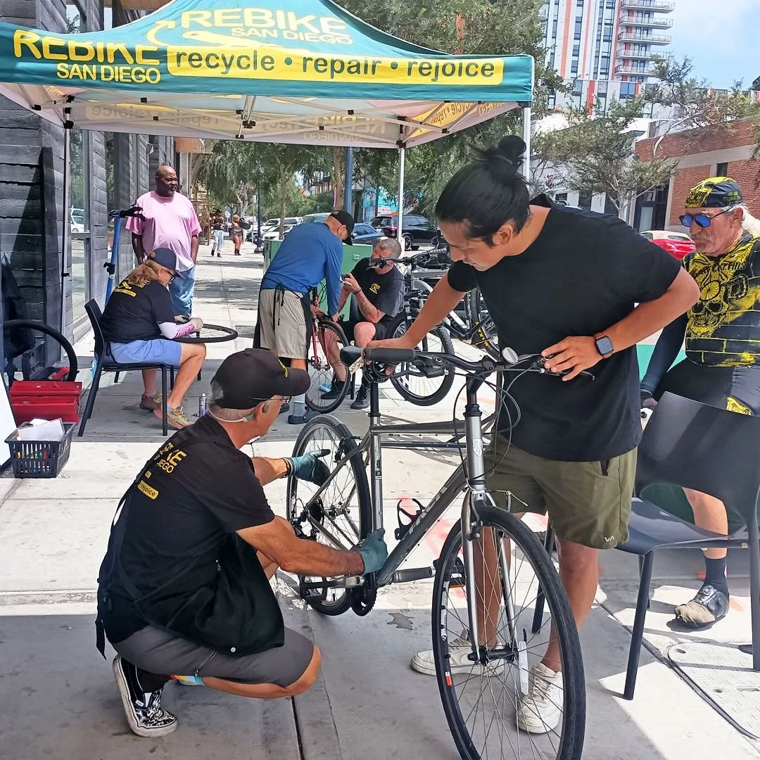 Volunteers fix bikes under the ReBike canopy at a Sunday clinic on 15th Street