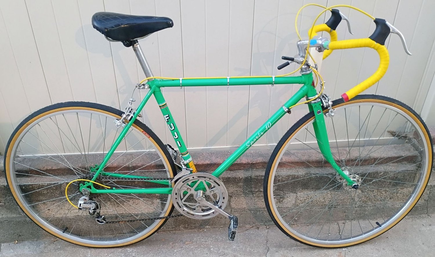 A green vintage Fuji road bike with yellow bar tape