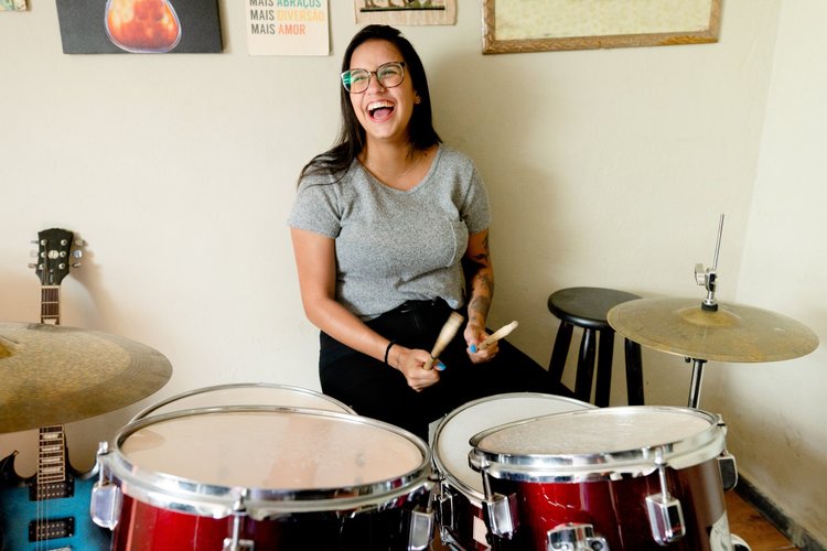 Smiling adult woman playing a drum kit at home