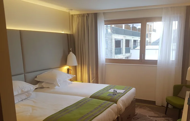 Our twin room at the resort: two beds with green throws, an armchair and a window onto the resort