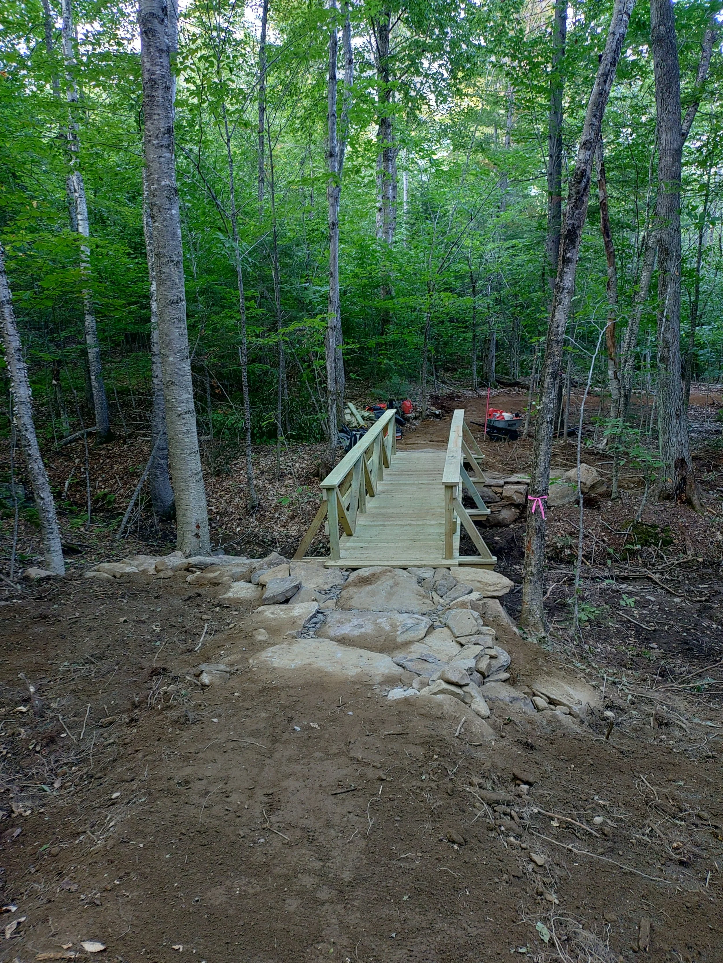a freshly constructed wooden bridge with railings on either side