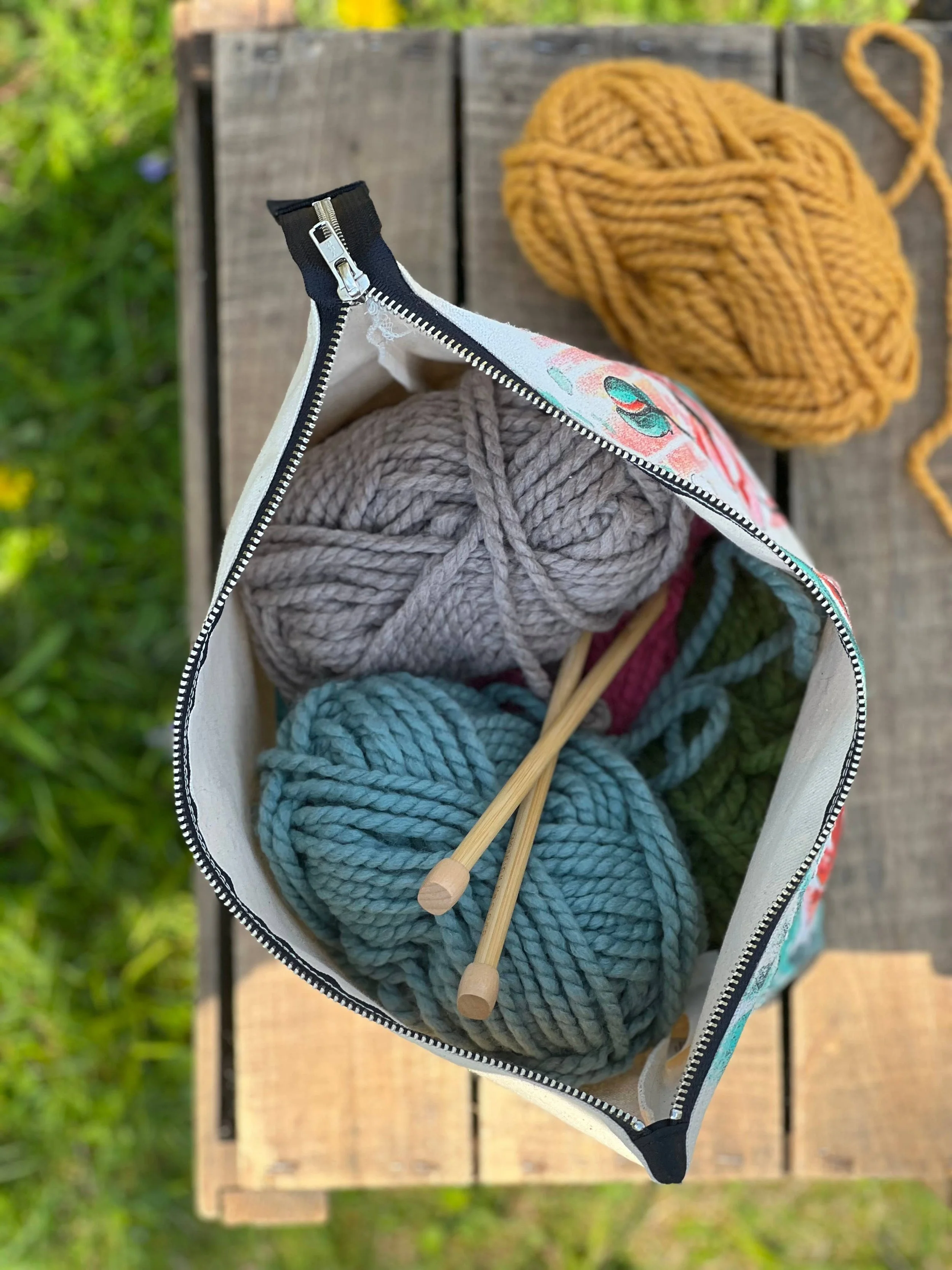 Sheep project bag holding yarn and knitting needles for a tidy portable setup