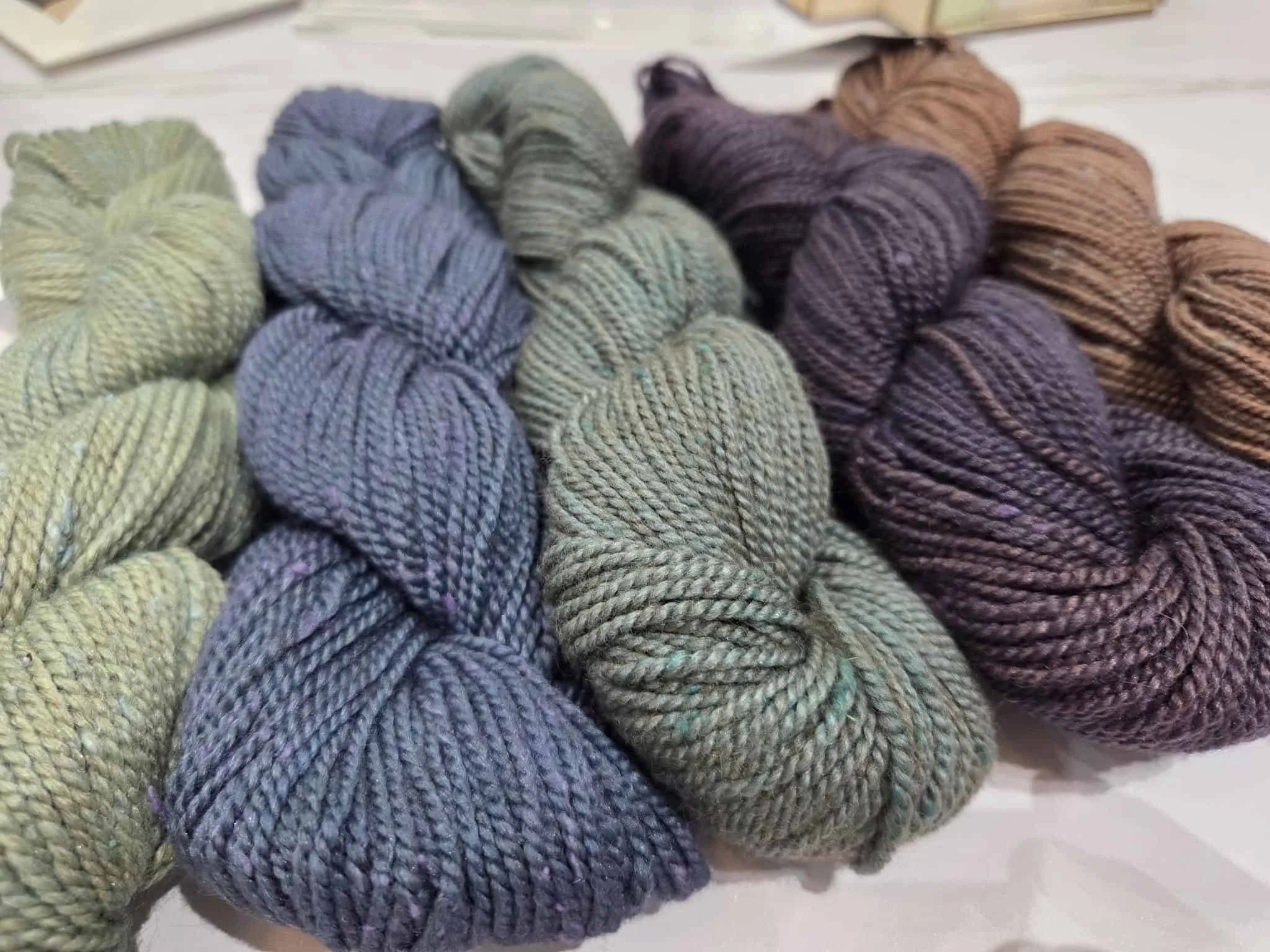 Hand-dyed yarn skeins in earthy tones on display at AriYARN
