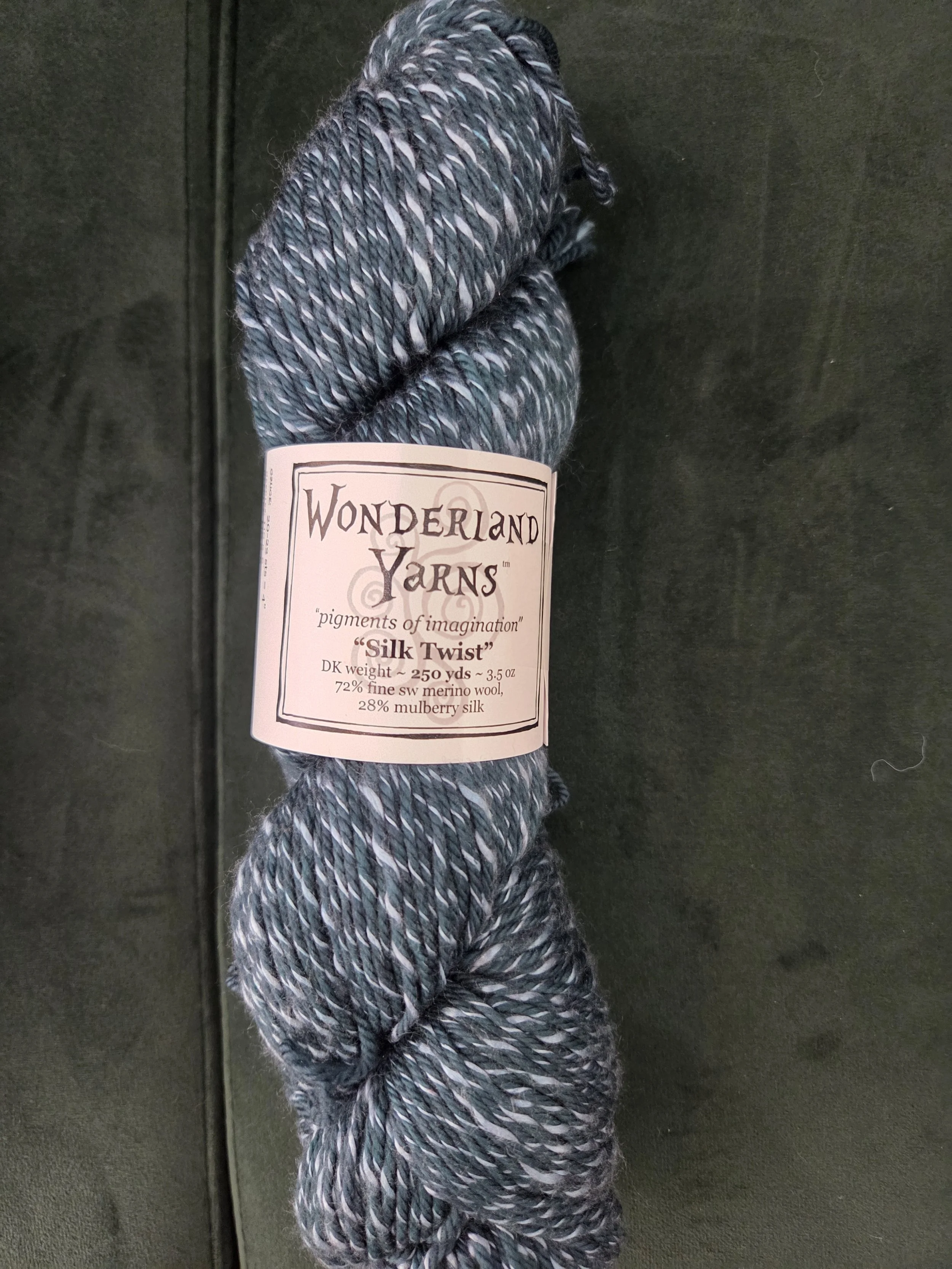 Wonderland Yarns Silk Twist DK weight yarn in teal and gray marled colorway with label showing Category 3 light worsted weight