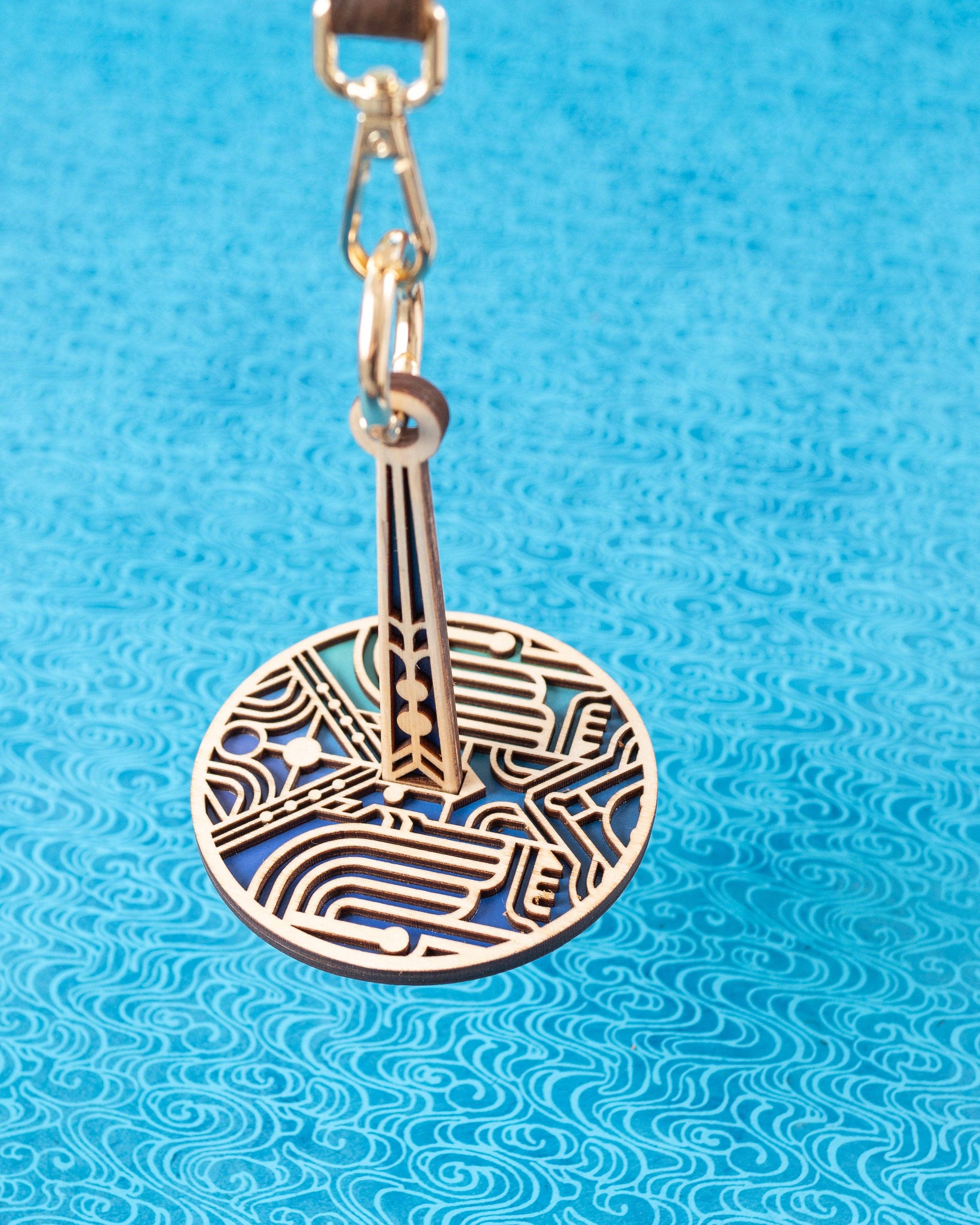 Art deco round stitch marker pendant with gold clip on blue backdrop, Lemonwood-style