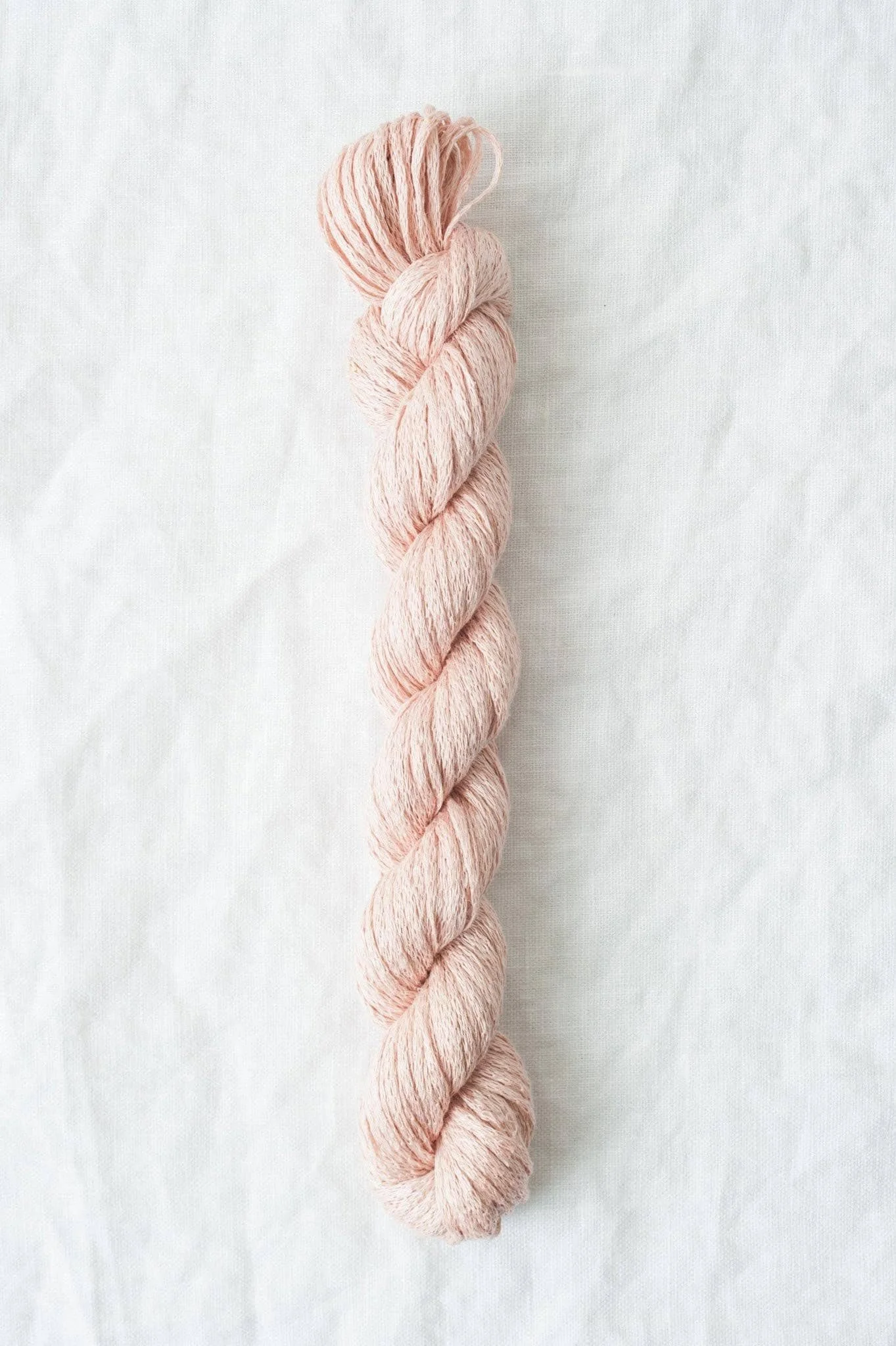 Pink organic yarn with visible twist and smooth finish for lightweight garments and accessories.