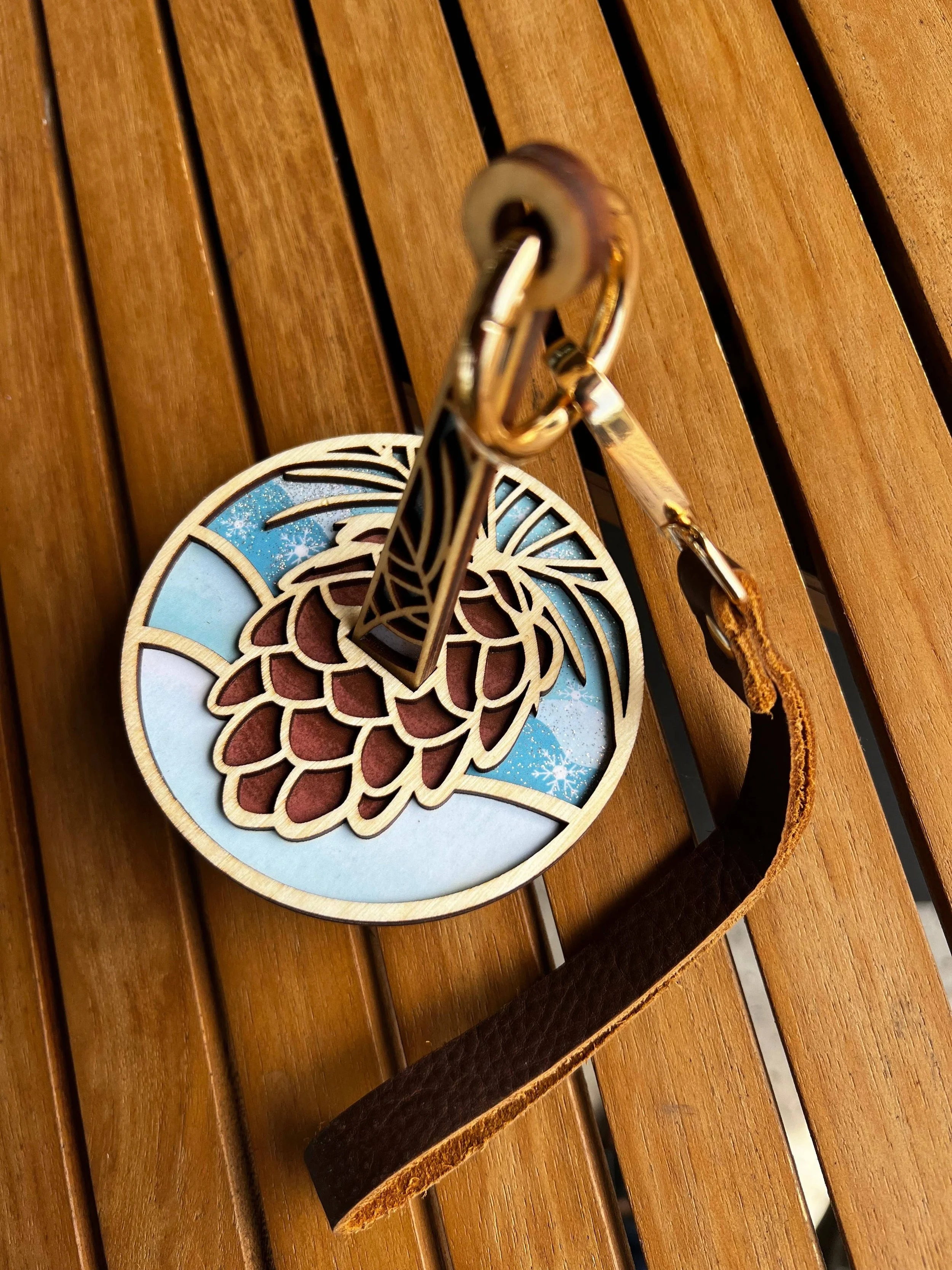 Layered pinecone wooden knitting accessory with blue inlay and brass ring