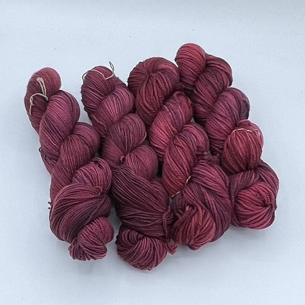 Gnome Depot DK-weight yarn skeins in deep red and rich warm tones.