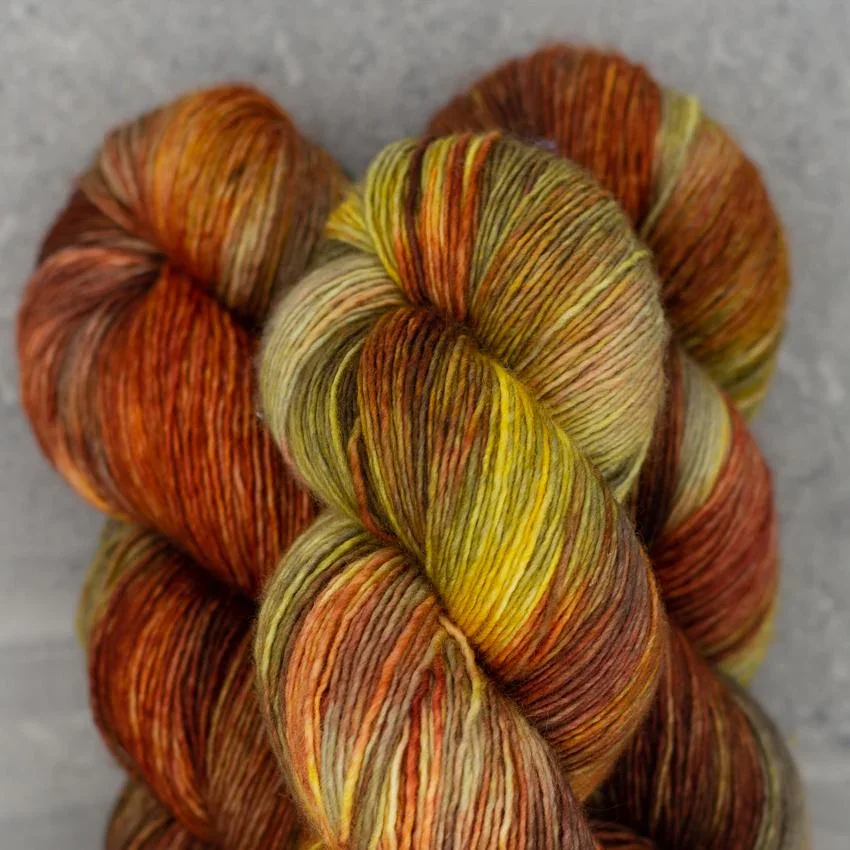 Madelinetosh sock-weight yarn skein in fall tones of green, yellow, and brown