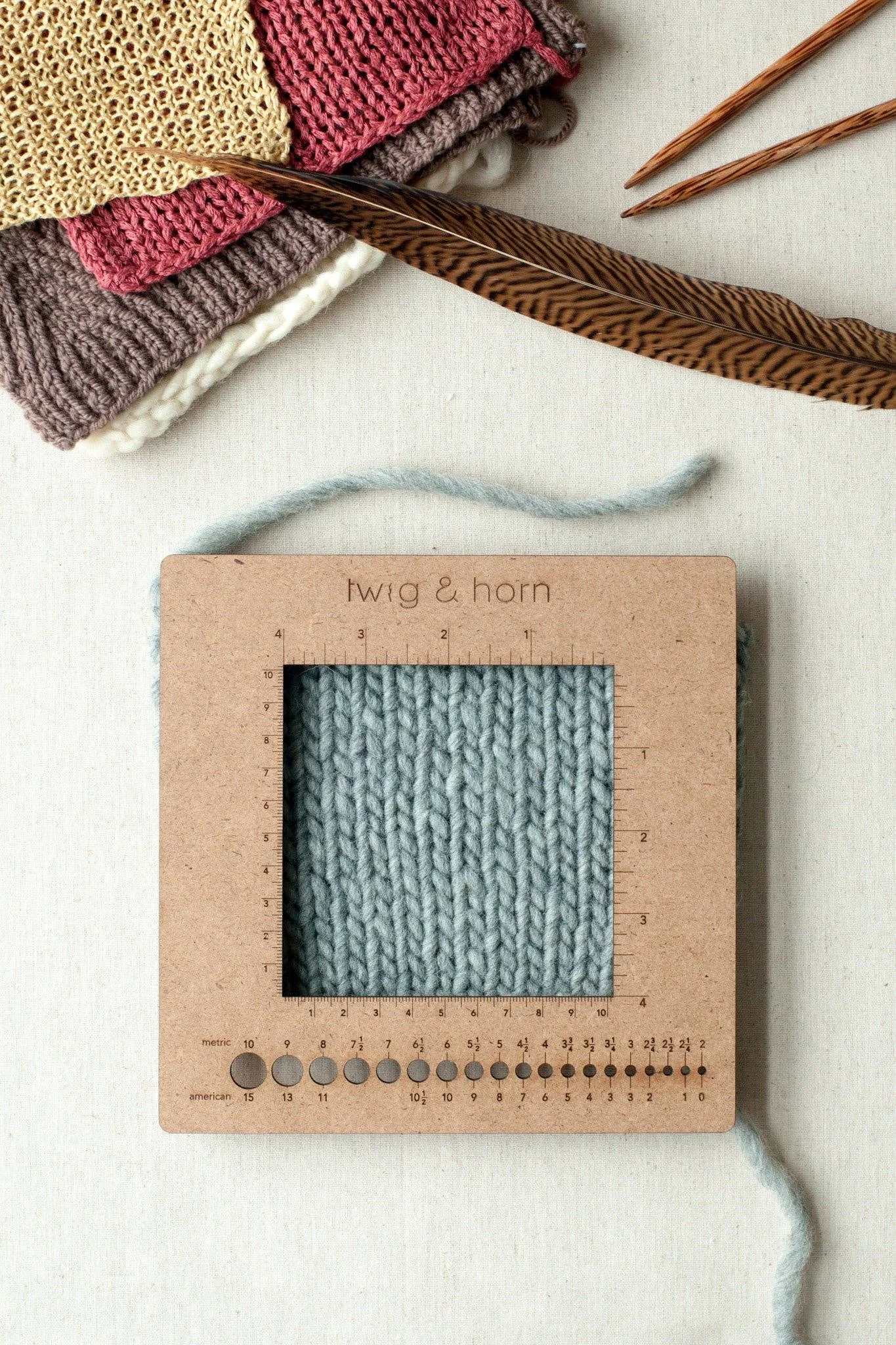 Square gauge ruler over a light-blue swatch for checking stitch and row gauge accurately.