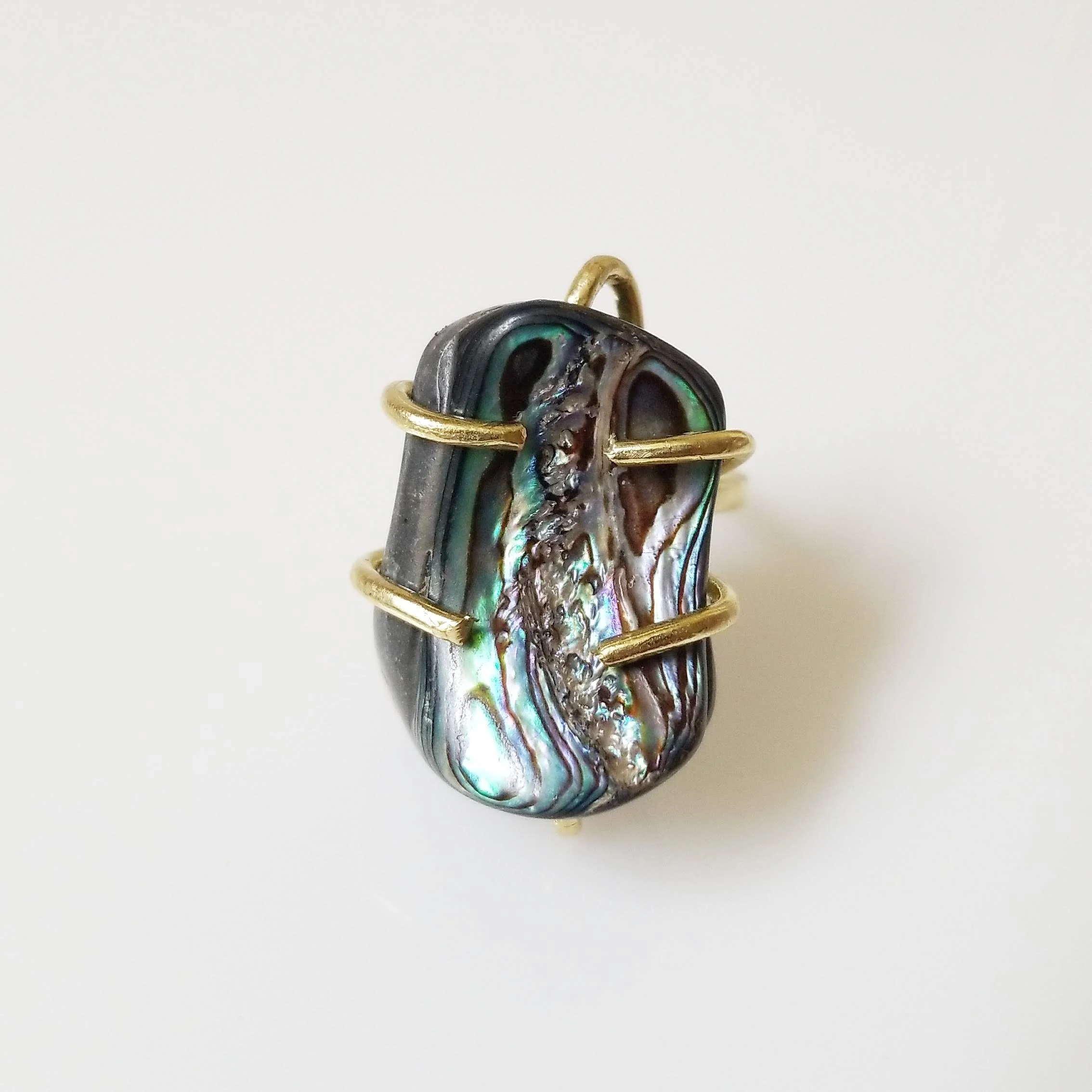 Close-up of a wire-wrapped rainbow abalone ring set in brass.