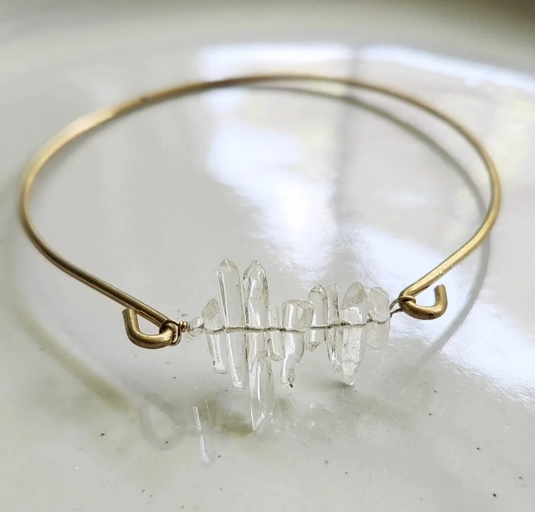 Delicate bangle bracelet with a clear quartz point cluster wrapped in gold-tone wire.