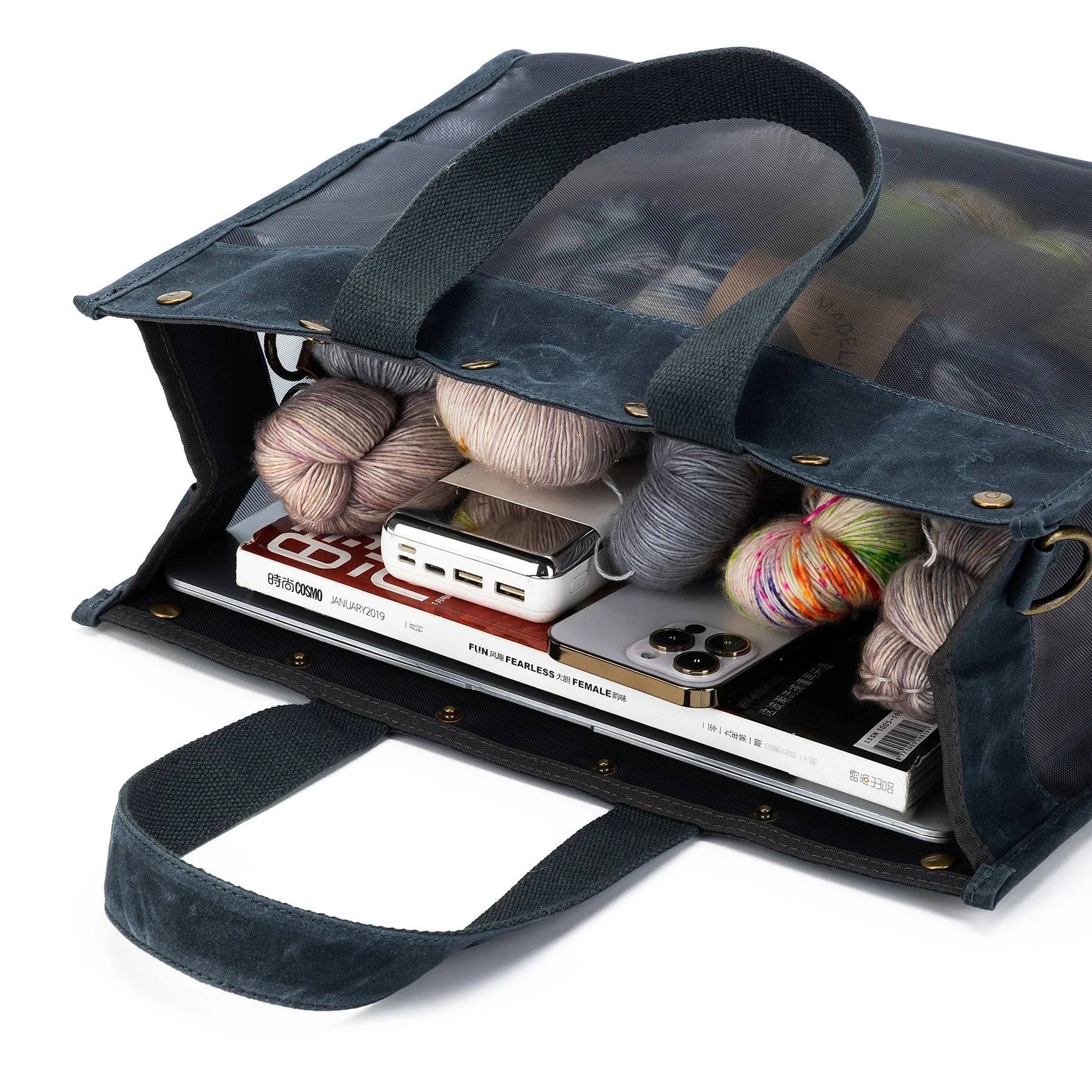 side view of a della Q Maker’s Mesh Tote holding yarn and fiber tools for knitting or crochet
