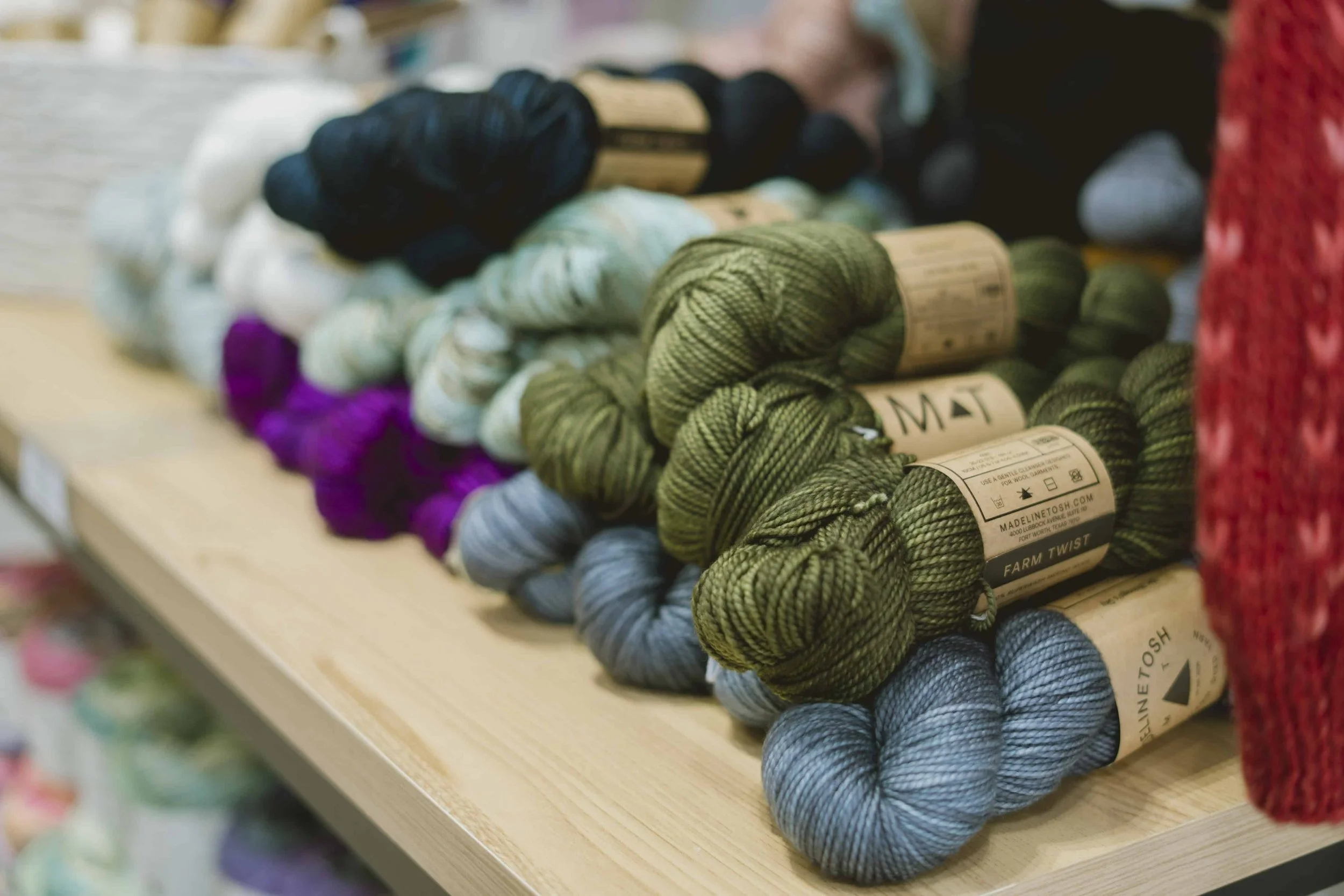Close-up of hand-dyed yarn skeins in warm tones at AriYARN yarn store.