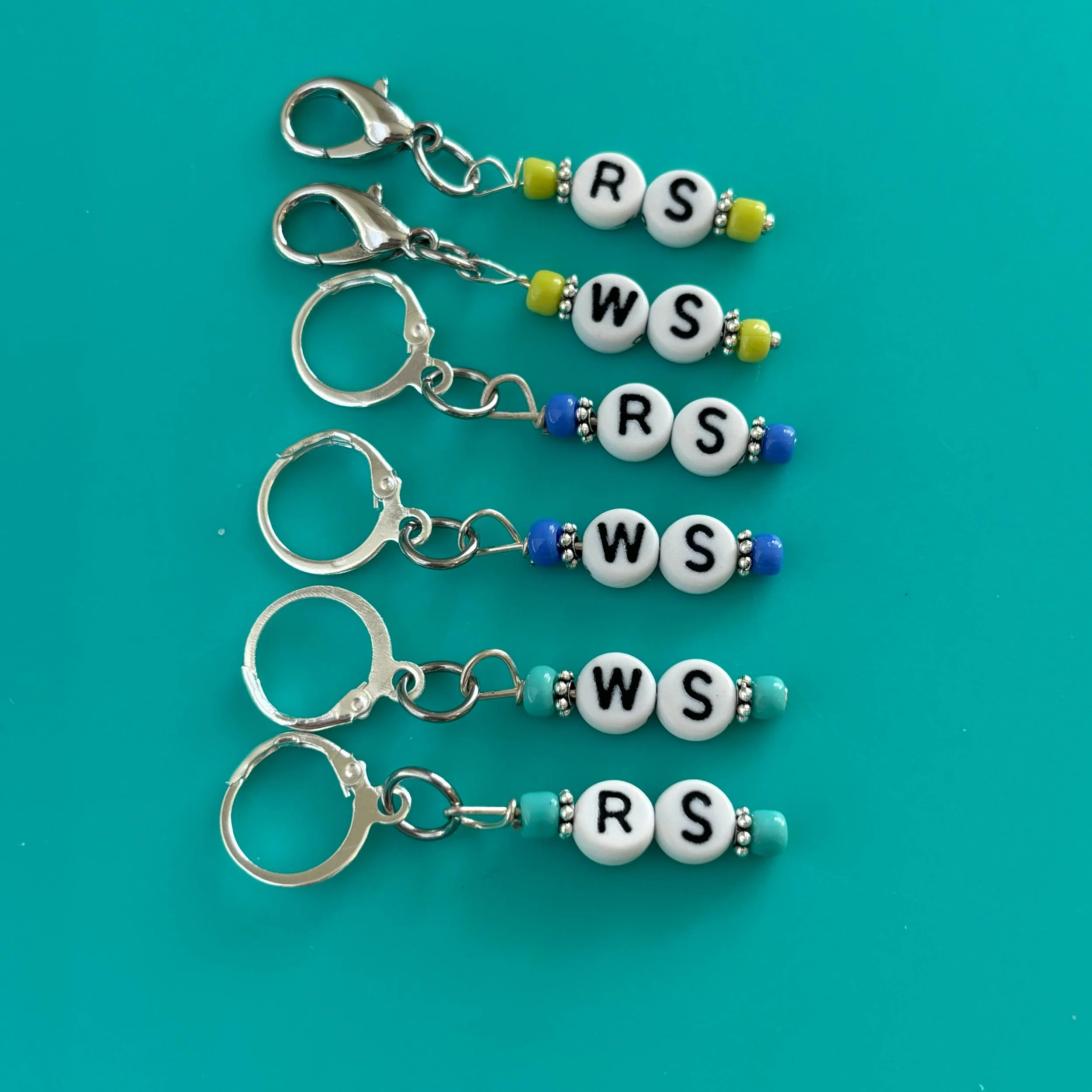 Lobster clasp stitch markers and progress keepers in a tray.