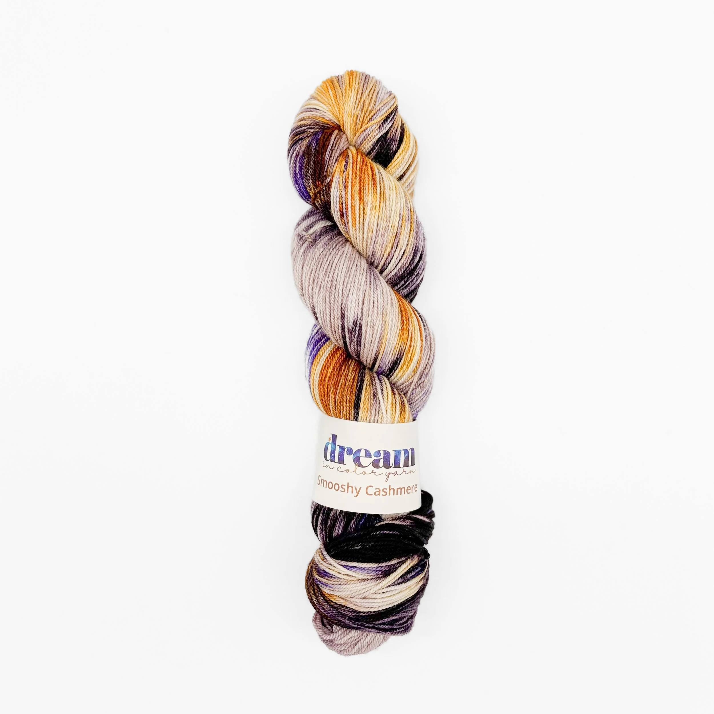 Hand-dyed luxury yarn skein with brown, purple, and creamy highlights (texture close-up)