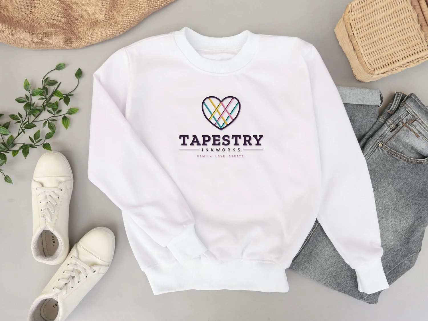 White sweatshirt embroidered with the Tapestry Inkworks logo
