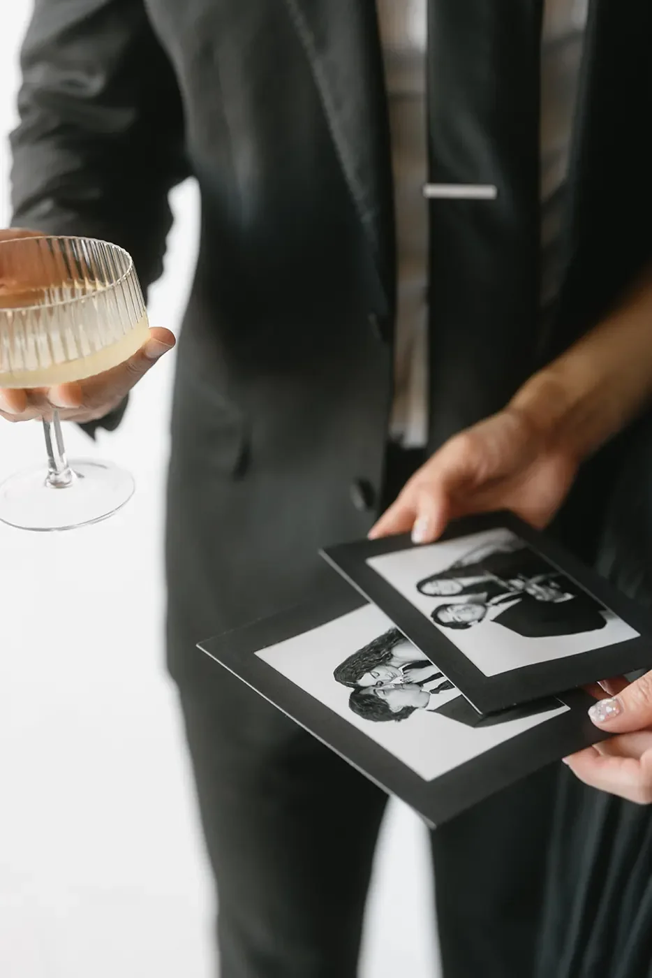 Guest in a black suit holding a black and white 4x6 photo booth print with a coupe glass at a formal event