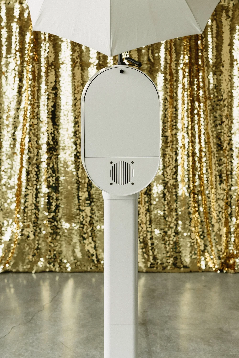 The digital photo booth set up in front of a gold sequin backdrop