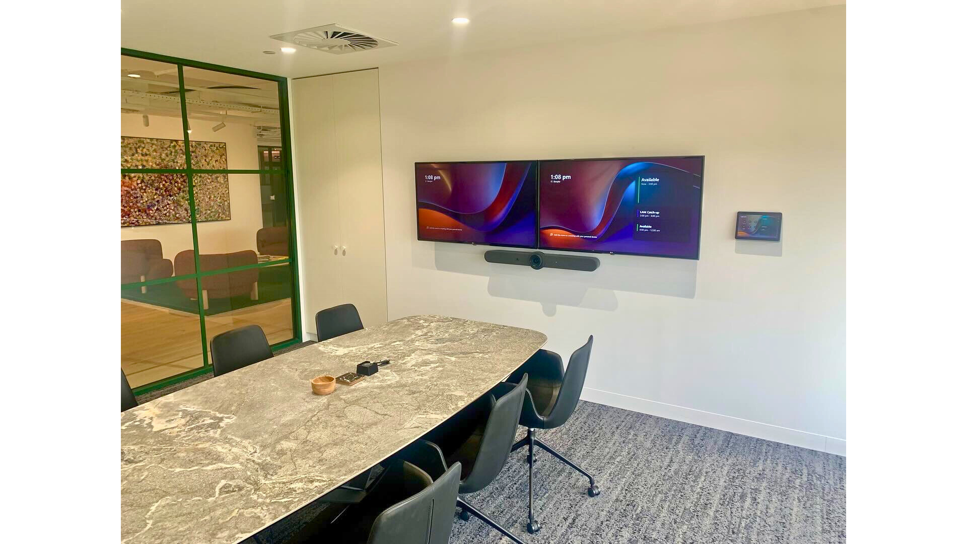 A modern meeting room with dual displays, collaboration technology and a large meeting table.