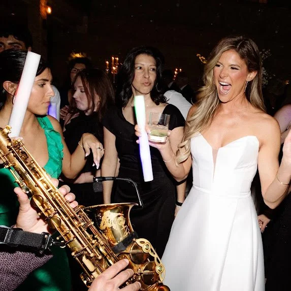 Bride celebrating on the dance floor with live saxophone entertainment