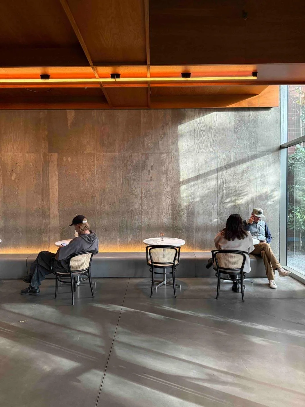 A quiet room with people working at small tables in warm light