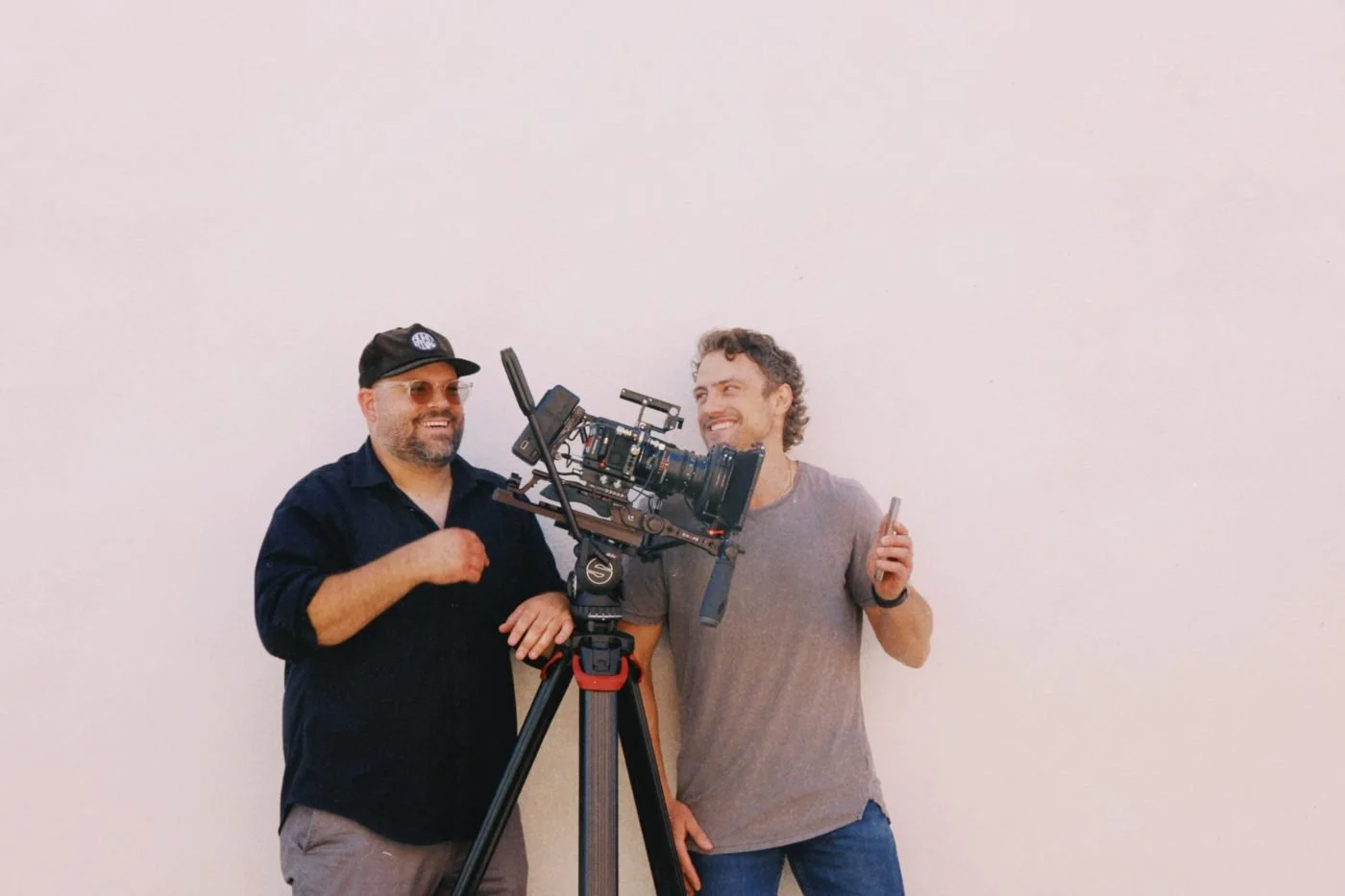 Two Rogue Dynamics crew members behind a camera on a white-wall set