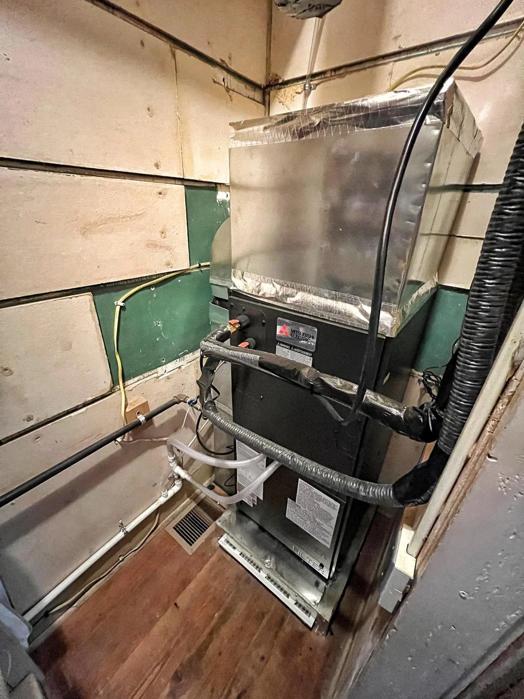 Mitsubishi indoor air handler installed in a utility space, connected to existing ductwork