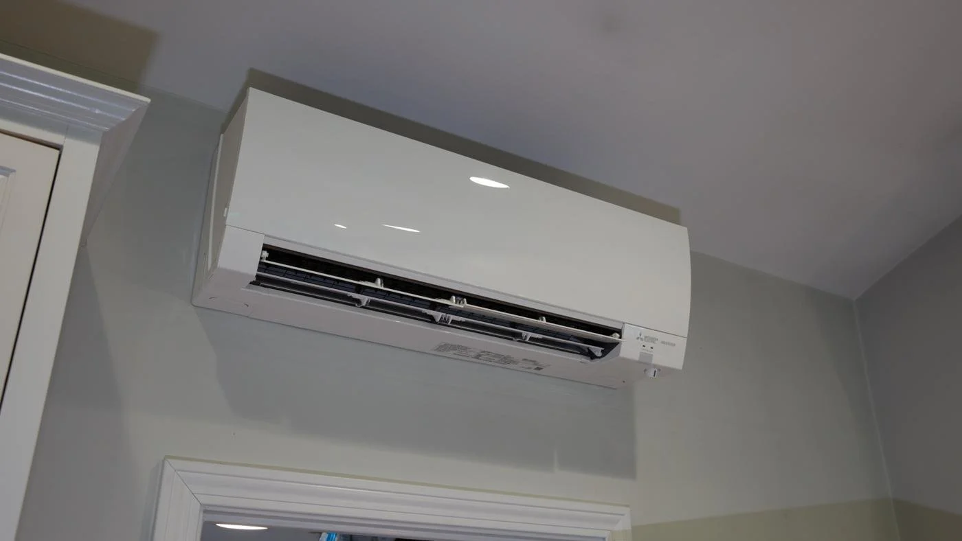 Wall-mounted Mitsubishi indoor unit high on the wall of a room above a doorway