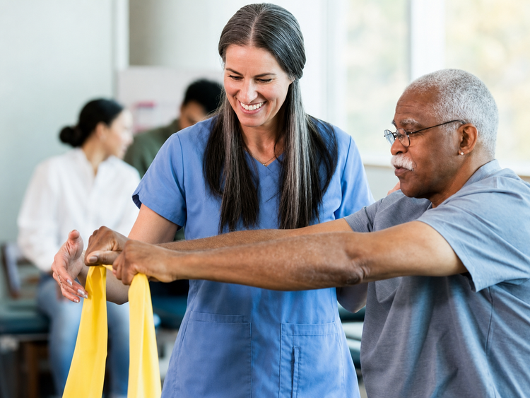 An occupational therapist guiding an older adult during a therapeutic resistance-band activity